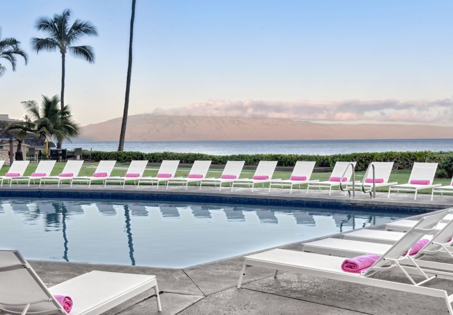 Lounge chairs with pink beach towels setup around a pool