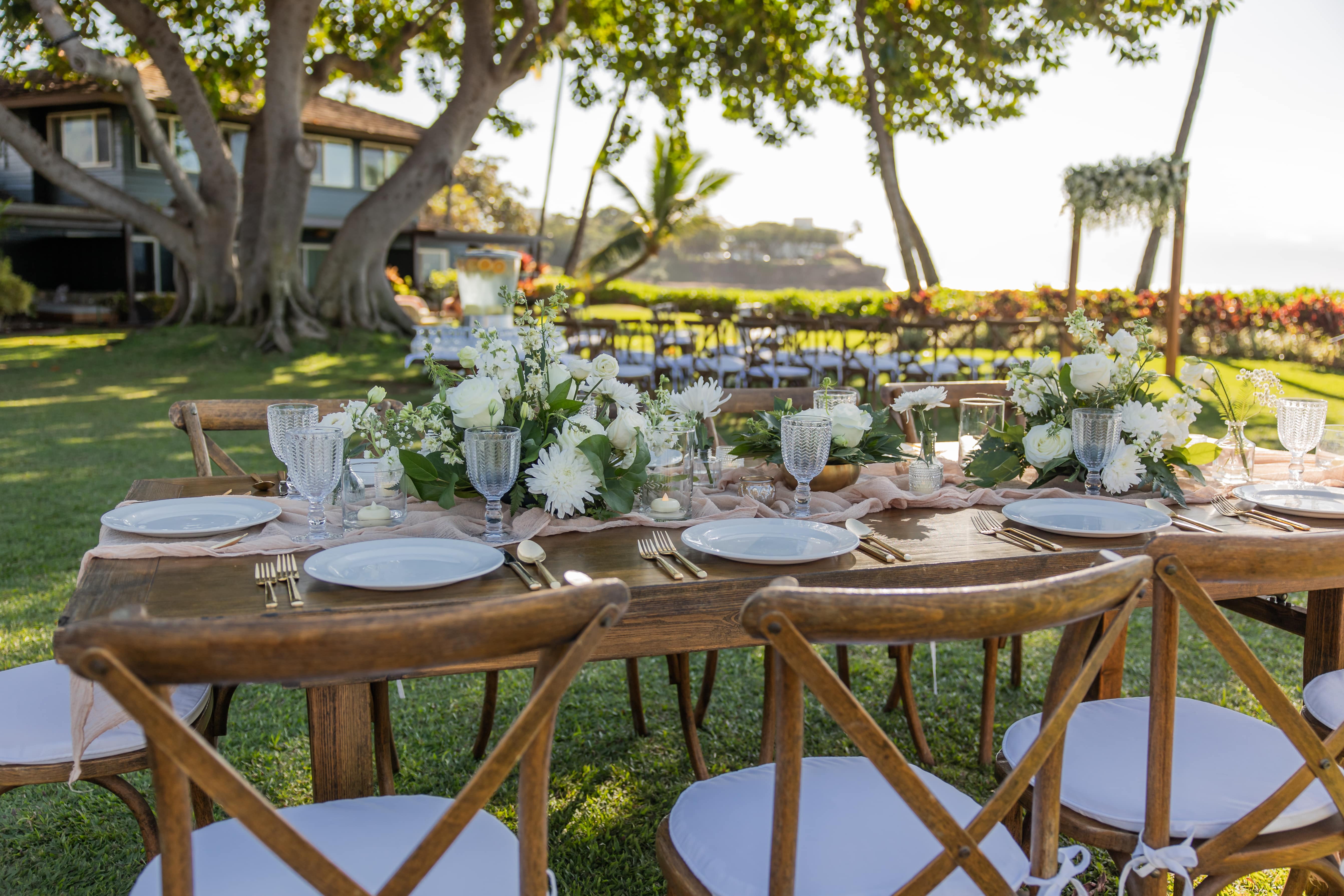 A beautifully set outdoor dining table with white flowers and candles