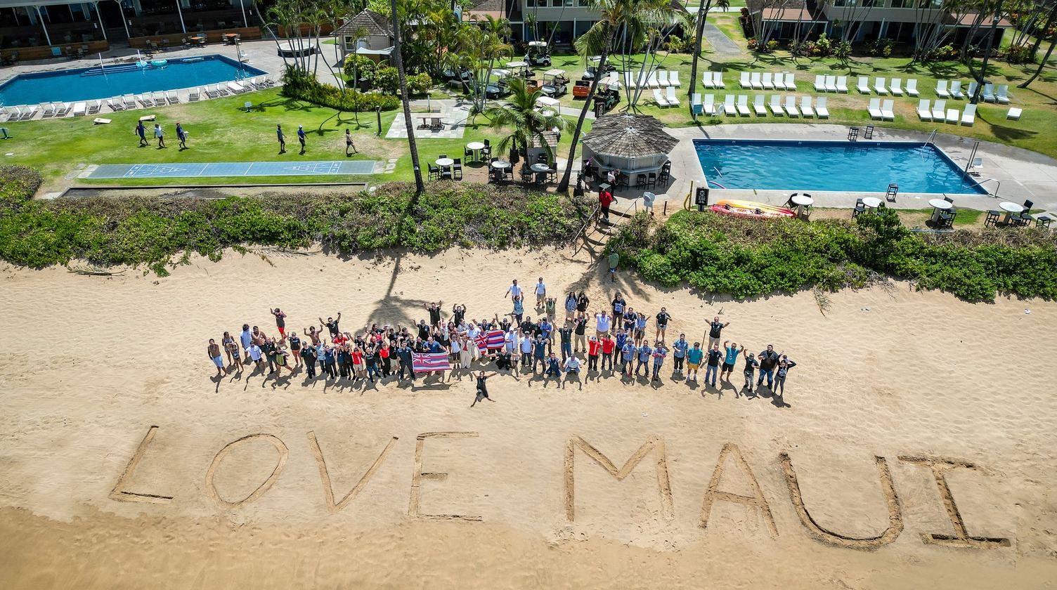 Image of people standing on the beach with the word Love Maui written on it.